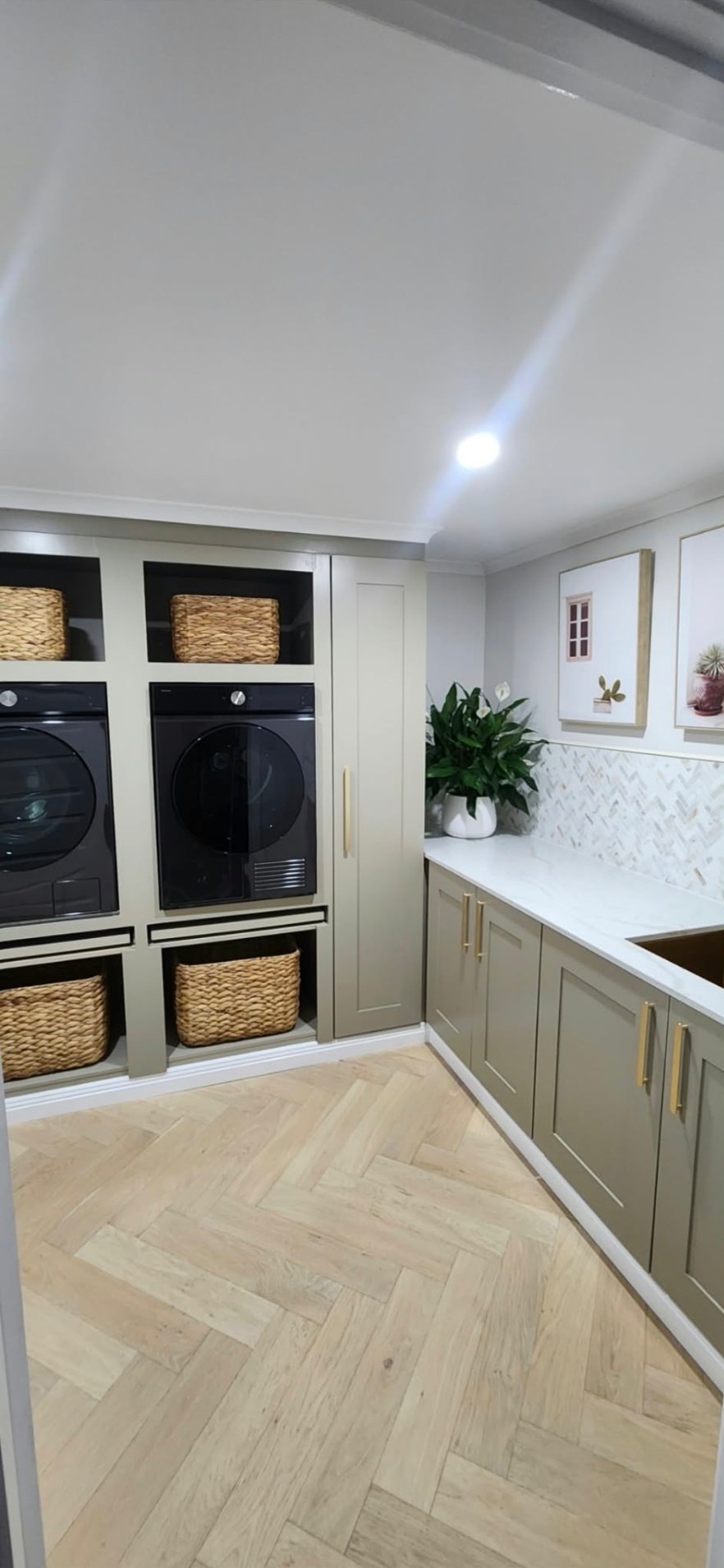 Finished laundry with shaker cabinetry, stone benchtop and herringbone floor