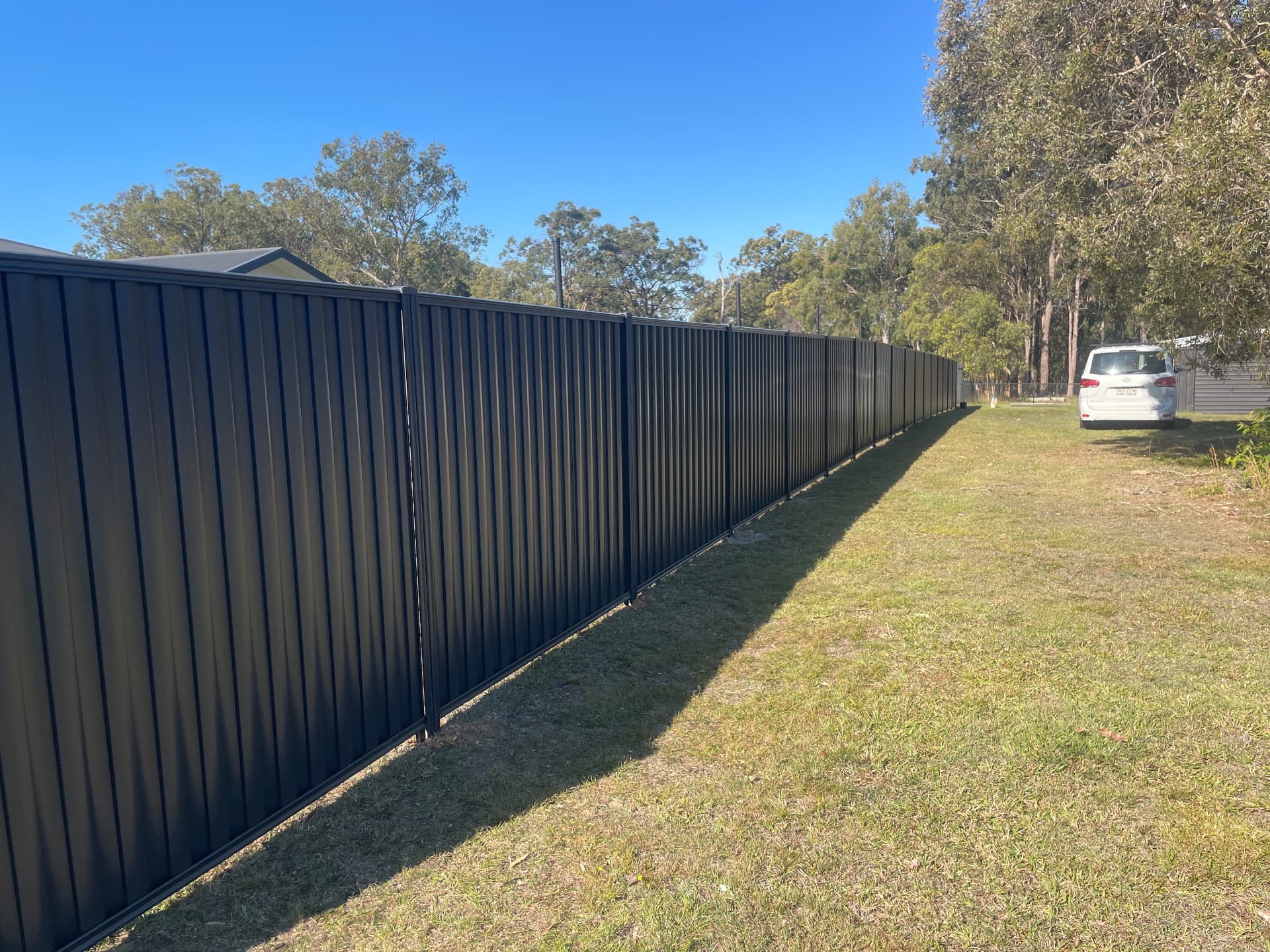 Long run of new black Colorbond boundary fencing